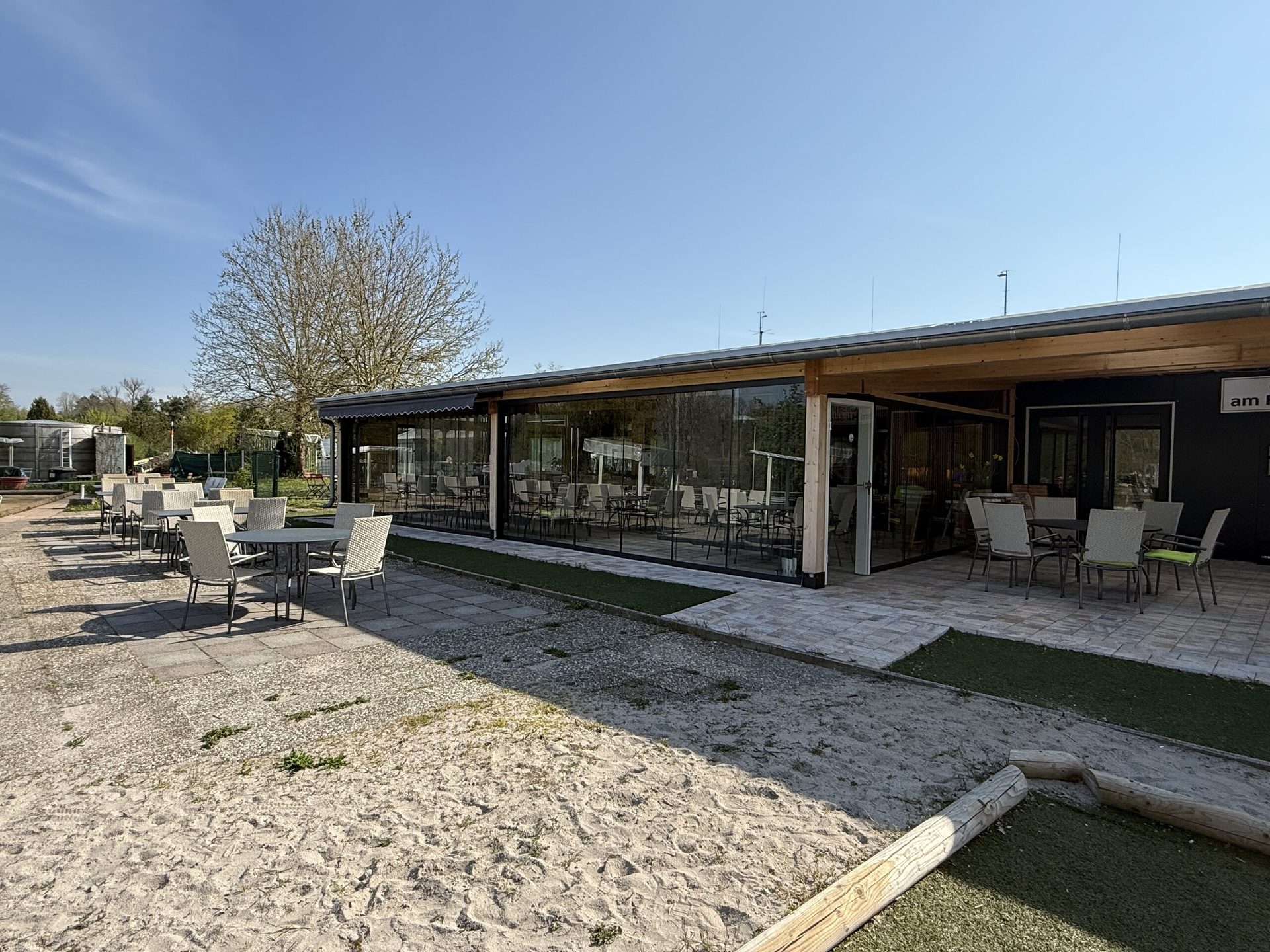 Die Gaststätte mit Glasfront, Holzdach und Terrasse
