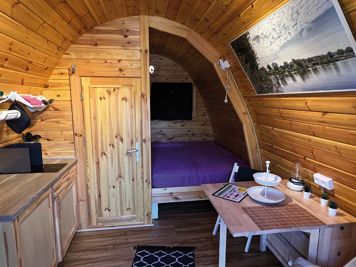 Campingpod von innen: Küchenzeile, Esstisch und Doppelbett im Rundgewölbe