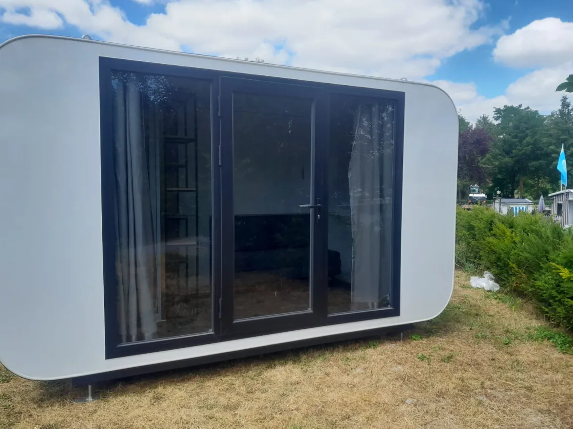Campingcube Luna — weisser Cube mit grosser Fensterfront auf der Wiese