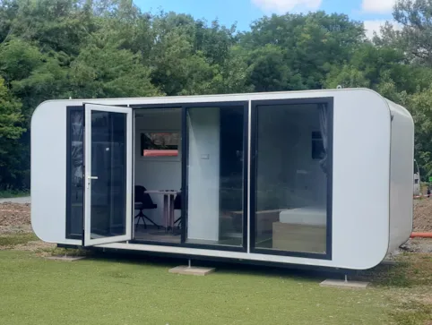 Campingcube Orion — Cube mit geoeffneter Tuer, Blick auf Sitzecke und Bett