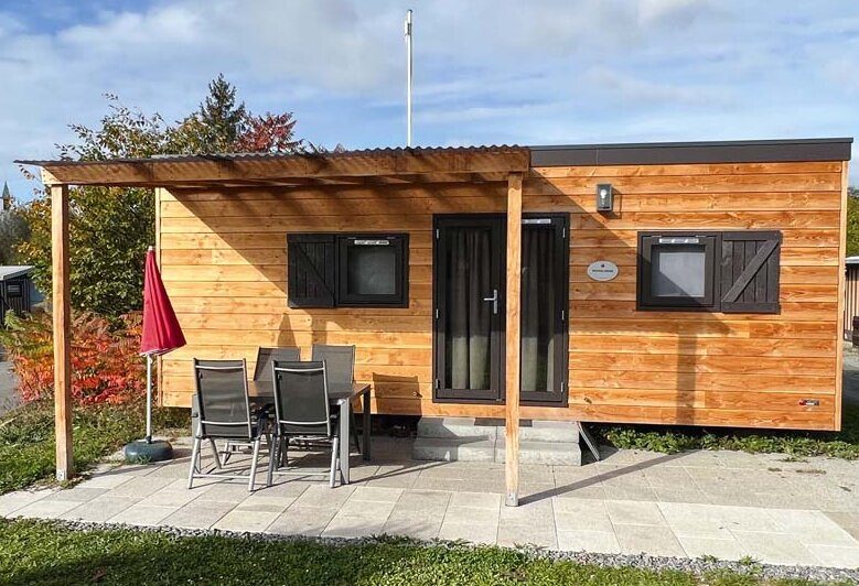 Woodlodge von aussen: Holzhütte mit überdachter Terrasse, Tisch und Stühlen